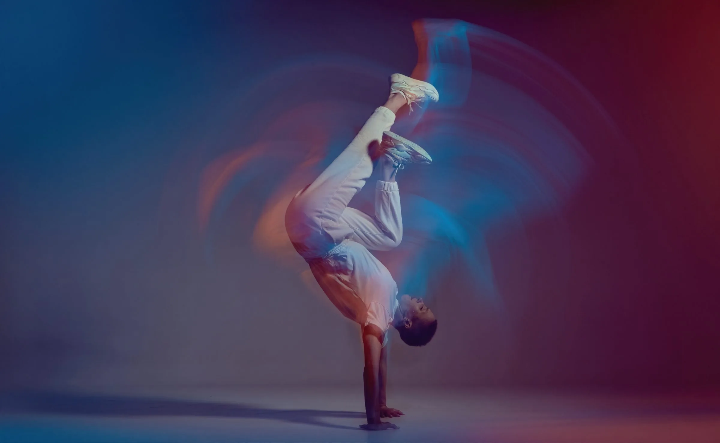 Breakdancer in a one-hand handstand with motion trails